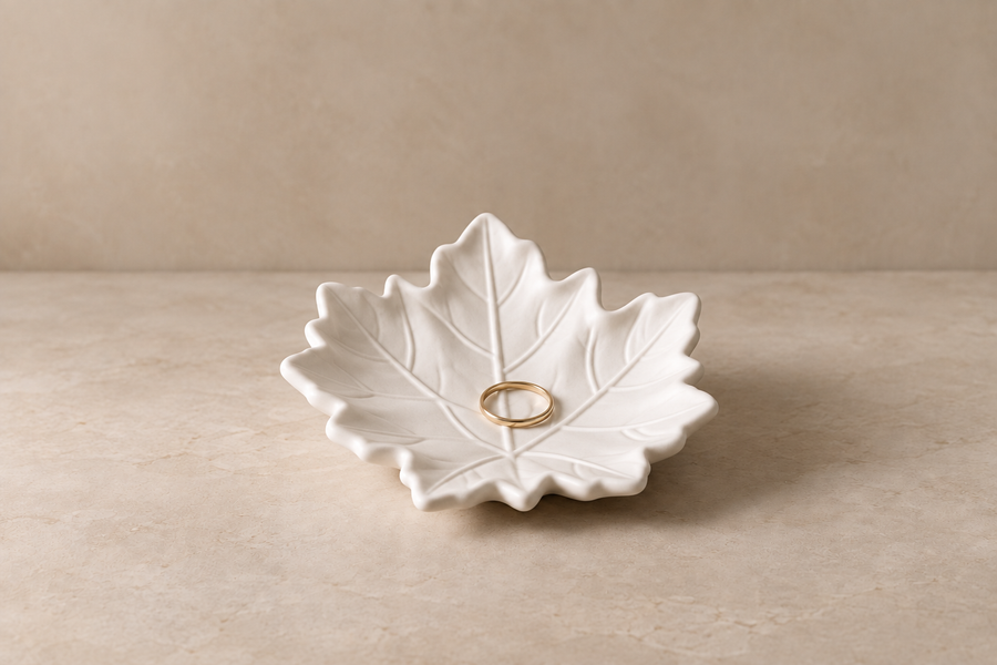 White leaf jewellery dish holding a gold ring
